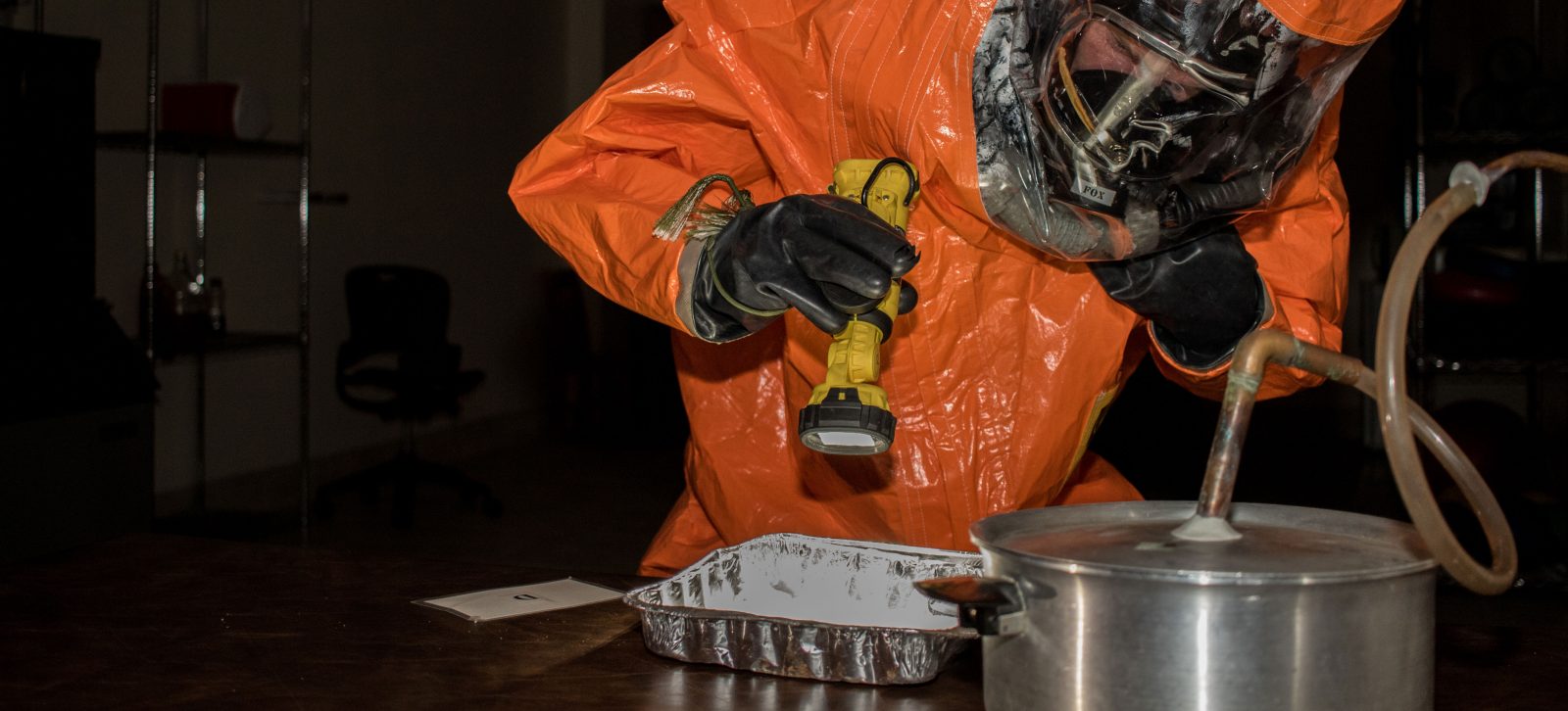 person in hazard suite examining weapons materials